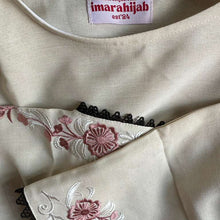 Load image into Gallery viewer, Close-up of a garment with floral embroidery and a visible brand label.
